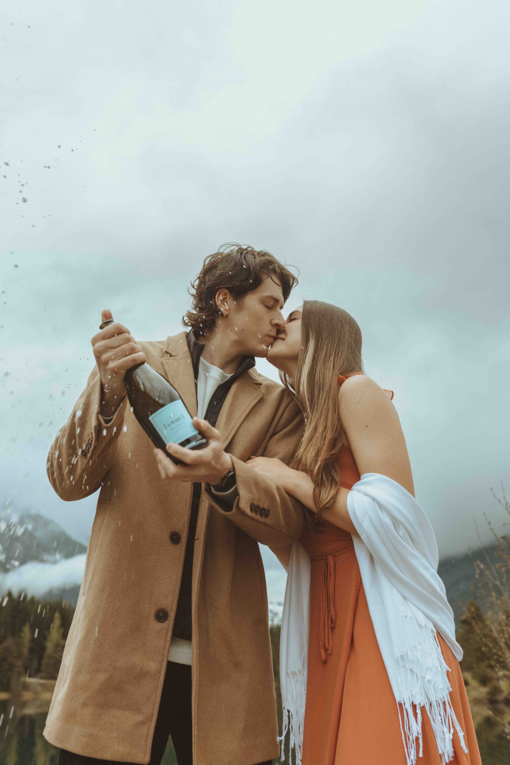 Happy Couple Popping a Bottle of Champagne During Engagement Photos