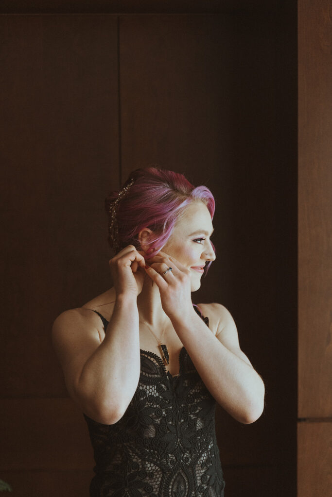 bride putting on her winter elopement earrings