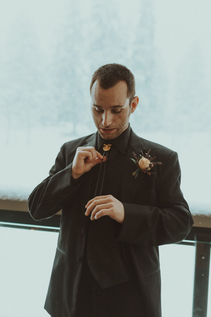 groom getting ready for his winter elopement ceremony