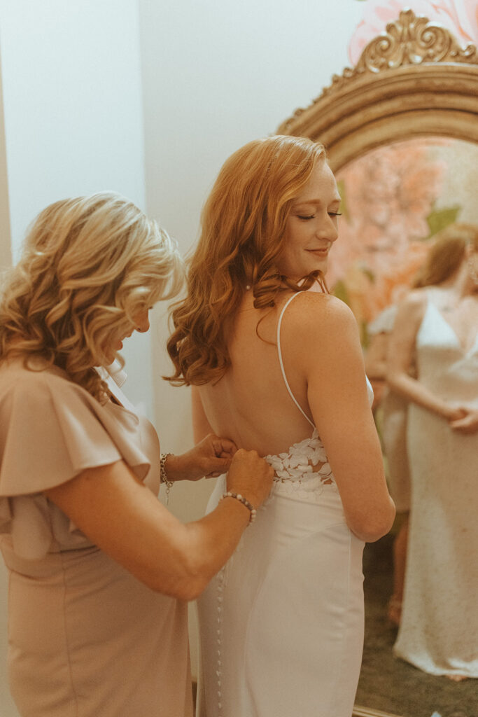 mother of the bride helping her with the wedding dress