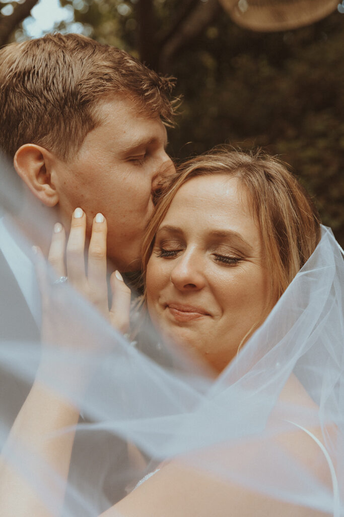 groom kissing the bride on the cheek