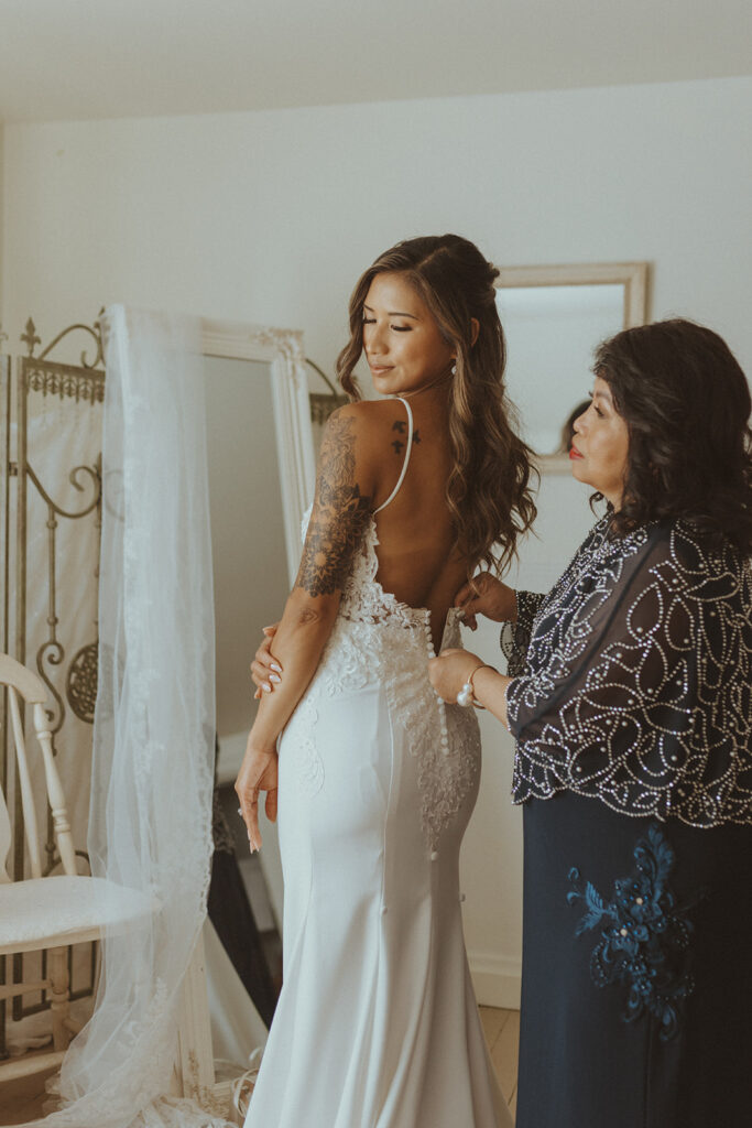 mother of the bride helping her with the wedding dress