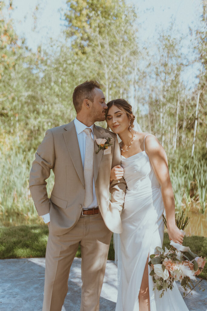 groom kissing the bride on the cheek at their dream backyard wedding